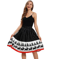A woman with long hair stands smiling while holding the sides of her knee-length skirt. The skirt, a ladies' Christmas print stretch high waist design, features black fabric adorned with white polka dots and a festive border of reindeer and trees. She complements the look with a black sleeveless top, and the skirt is finished off with a red hemline for added cheer.