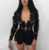 A woman with long dark hair stands against a white brick wall. She is wearing a 2 Piece V-Neck Slim Long Sleeve Hollow Out Lace Cardigan, which reveals some skin through its intricate floral patterns. The cardigan features a plunging neckline and is form-fitting. Only the upper torso and thighs are visible.