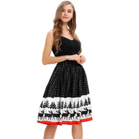 A woman with long hair is wearing a sleeveless black top paired with the skirt women's ladies Christmas print knee-length skirt. The festive skirt, decorated with reindeer, trees, and snowflakes, features a charming red hem at the bottom. She stands against a white background, smiling brightly with her hand on her hip.